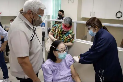  ?? (Angeles City Informatio­n Office) ?? JAB FOR MOM. Angeles City Mayor Carmelo 'Pogi' Lazatin, Jr. watches as his mother, 82-year-old Illuminada Lazatin gets her first dose of vaccine at the City College of Angeles on Thursday.