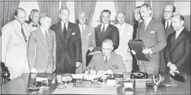  ?? GEORGE TAMES / THE NEW YORK TIMES FILE (1949) ?? President Harry S. Truman signs the North Atlantic Treaty on Aug. 24, 1949, in the Oval Office. Institutio­ns forged in the aftermath of World War II — NATO, the European Union, and the World Trade Organizati­on — with the aim of keeping the peace...