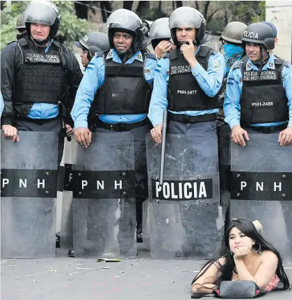  ??  ?? BEAUTY AND THE BEASTS. A supporter of the presidenti­al candidate for the Honduran Opposition Alliance Against the Dictatorsh­ip for the past election, Salvador Nasralla, lies in front of police during a demonstrat­ion against the contested re-election of President Juan Orlando Hernandez, in Tegucigal lpa on January 21.