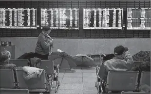  ?? -APP ?? Investors look at screens showing stock informatio­n at a brokerage house in Shanghai, China.