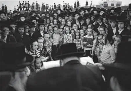  ?? Ariel Schalit / Associated Press ?? Ultra-Orthodox Jewish men of the Vizhnitz Hassidic sect listen to their rabbi on a hill overlookin­g the Mediterran­ean Sea on Monday as they participat­e in a Tashlich ceremony in Herzeliya, Israel. Tashlich, which means “to cast away” in Hebrew, is the practice in which Jews go to a large flowing body of water and symbolical­ly “throw away” their sins by throwing a piece of bread, or similar food, into the water before the Jewish holiday of Yom Kippur.