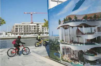  ?? KAMRAN JEBREILI/AP ?? Bikers pass a billboard advertisin­g a future housing project Jan. 31 in Dubai, which is seeing a building boom.