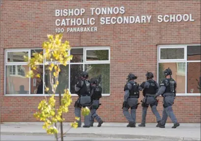  ??  ?? A tactical team heads into Bishop Tonnos Catholic Secondary in Ancaster. Students hid under desks and others barricaded doors during a manhunt.