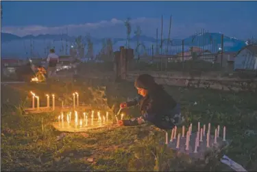  ?? (AP/Dar Yasin) ?? A Kashmiri Shiite Muslim girl lights candles at the grave of her relative to mark Shab-e- Barat, on the outskirts of Srinagar, Kashmir. Muslims visit ancestral graveyards for the salvation of the souls of the departed and also believe that all sins will be forgiven by praying to Allah throughout the Shab-e Barat night.