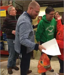  ?? SUSAN L. SERBIN - MEDIANEWS GROUP ?? Order is everything as Matt Owens, center, has the list of foodstuffs being packed for holiday boxes. Owens and John Gildea-Walker, right, will taking over the Springfiel­d School District Turkey Fund leadership on the retirement of Dave Ash, at left.