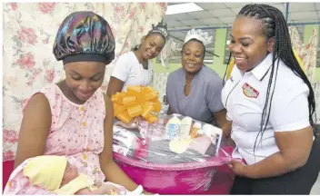  ?? ?? First New Year baby
Nickay Martin looks endearingl­y at her newborn, Ariya Gordon, who arrived weighing 3.4 kg at 12:55 am on January 1, 2023, the first for the new year at the Spanish Town Hospital, St Catherine. Toyna Sherman of Kirk-fp Limited (right) presents her with a hamper of baby products as Kerrian Lawes (second left), registered nurse and Jannette Hendricks-graham, department­al nurse manager and coordinato­r of the maternal unity, look on.