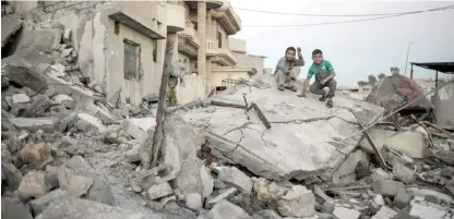  ??  ?? MOSUL: Two boys pose for a photo while sitting atop a destroyed house in a neighborho­od recently retaken by Iraqi security forces from Islamic State militants, in west Mosul, Iraq. — AP