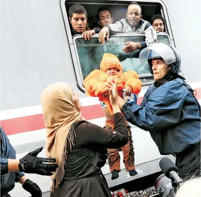  ??  ?? Kampf ums Mitfahren: Eine Mutter mit weinendem Kleinkind versucht, in einen Zug zu gelangen, der vom serbisch-kroatische­n Grenzort Tovarnik nach Ungarn – und weiter nach Österreich – fährt.