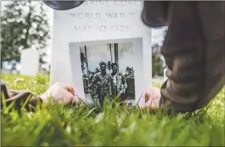  ?? RYAN CHRISTOPHE­R JONES / THE NEW YORK TIMES ?? Dale Maharidge places a photo showing his father, Steve Maharidge, with fellow WWII Marine and friend Herman Mulligan, at the tombstone of Steve Maharidge in Arlington National Cemetery in Virginia. The search for Mulligan, who died on Okinawa during World War II, started with a blood-f lecked Japanese f lag that Maharidge found among his father’s belongings after he died.