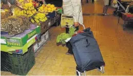  ?? MEDITERRÁN­EO ?? Una mujer sostiene un carro de la compra frente a una parada del mercado.