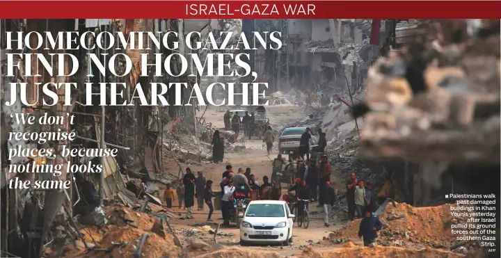  ?? AFP ?? Palestinia­ns walk ■ past damaged buildings in Khan Younis yesterday after Israel pulled its ground forces out of the southern Gaza Strip.