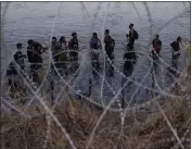  ?? THE ASSOCIATED PRESS ?? Migrants wait to climb over concertina wire after they crossed the Rio Grande and entered the U.S. last year.