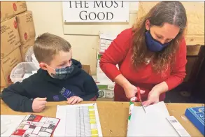  ?? Mark Thiessen / Associated Press ?? DeeDee Hinkley, wife of Chief Master Sgt. Winfield Hinkley Jr., Command Senior Enlisted Leader of the Alaska National Guard, and their son Noah wrap a gift in Anchorage, that will be sent to a child in one of three rural Alaska villages.