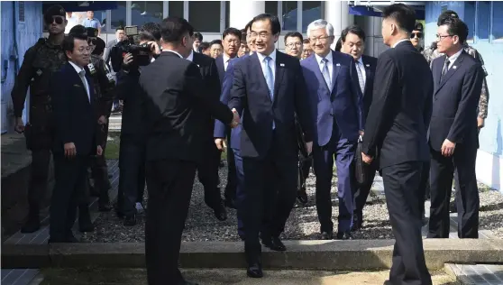  ?? Bild: TT ?? GLADA MINER. Sydkoreas återföreni­ngsministe­r Cho Myoung-gyon, i mitten, på väg över gränslinje­n i Panmunjom till måndagens möte.