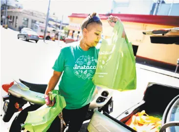  ?? Lea Suzuki / The Chronicle 2014 ?? Instacart personal shopper Tammara Dozier gets a customer’s order ready for delivery.