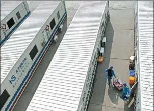  ?? TIAN XI / FOR CHINA DAILY ?? Medical workers transfer samples to be tested at a makeshift testing center in Lanzhou, Gansu province, on Saturday. Seven movable labs were deployed to Lanzhou to boost the city’s testing capacity.