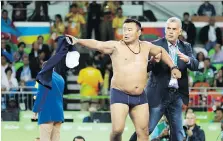  ?? THE ASSOCIATED PRESS ?? A wrestlling coach for Mongolia takes off his clothes in protest against a decision against his country’s wrestler.