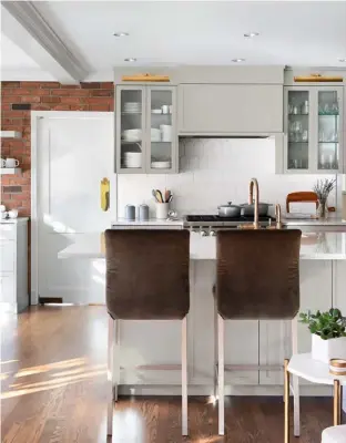  ??  ?? LEFT “The homeowner is incredibly organized, so she was a perfect candidate for glass-door cabinetry,” says Sarah. Library sconces, rather than inner-cabinet lighting, illuminate the breezy grey colour Sarah opted for here. Practicali­ty meets grace in the bar stools, which feature removable covers. “They’re Velcro, so you just pop them off and toss them in the wash.”