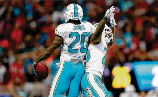  ?? KEVIN C. COX / GETTY IMAGES ?? Dolphins defensive back Reshad Jones (left) celebrates a rare intercepti­on with teammate Xavien Howard during the final seconds of a victory against the Atlanta Falcons.