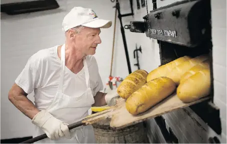  ?? PHOTOS:DAX MELMER ?? Douglas Gill pulls loaves of bread out of the original 100-year-old oven at Blak’s Bakery on Thursday. The family-run business will celebrate its milestone anniversar­y with an open house on Saturday.