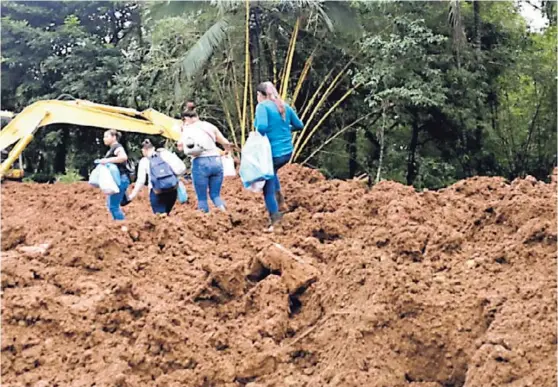  ?? REINER MONTERO ?? La caída de material sobre la ruta nacional 505, que comunica el centro de Sarapiquí con Quebrada Grande, en el distrito de La Virgen. Los vecinos deben caminar en medio del lodo para buscar, en el otro extremo, un taxi que los lleve a Puerto Viejo,...