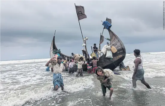  ??  ?? Noor Haba, 11, carries family belongings to the beach after the boat she travelled in landed at Shamlapur Beach.