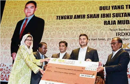  ??  ?? IRDK Land Group Director Datuk Mohd Shukri Dahlan (right) handing over a RM30,000 mock cheque to Yayasan Raja Muda Selangor executive director Aminah Abdul Rahim (left) after the opening of IRDKL Mall at Shah Alam, witnessed by Tengku Amir Shah (second...