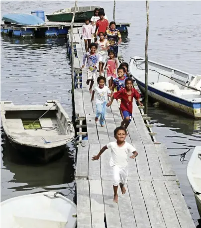  ??  ?? Orang asli children racing down a jetty at sungai Danga in Johor. Their families and others in the area depend largely on fishing and mussel farming for a livelihood. — Kenneth Wong/ The star