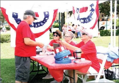  ?? The Sentinel-Record/Beth Reed ?? PATRIOTIC PICNIC: Steven Parker, left, buys a ticket for lunch from volunteer Coni Hall, right. Hall, as well as Kay Fischer and Sarah MaGee, volunteere­d during for the inaugural Red, White &amp; You Picnic in the Park on Arlington Lawn Wednesday, hosted by Friends of Hot Springs National Park. Donations and proceeds will go toward restoratio­n of the Maurice Bath House.