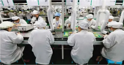  ??  ?? HUAIBEI: Chinese employees work on micro and special motors for mobile phones at a factory in Huaibei, east China’s Anhui province. — AFP