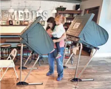  ?? CHARLES BERTRAM, AP ?? Courtnie Coulson votes with her 2-year-old daughter Molly in her arms in Lexington, Ky., on Tuesday.