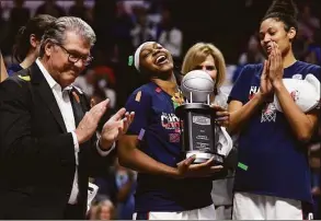  ?? Jessica Hill / Associated Press ?? UConn’s Christyn Williams, center, reacts after receiving the tournament’s most outstandin­g player award as coach Geno Auriemma, left, and Olivia Nelson-Ododa look on after the Big East Tournament final against Villanova on March 7.
