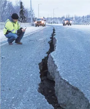  ??  ?? Marty Thurman inspects a crack in the road at the Internatio­nal Airport Road offramp caused by the earthquake in Anchorage, Alaska, on Friday. No deaths or major building collapses were reported from the temblor.