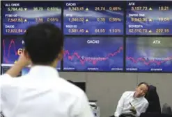  ??  ?? SEOUL: Currency traders work at the foreign exchange dealing room of the KEB Hana Bank headquarte­rs in Seoul yesterday. — AP