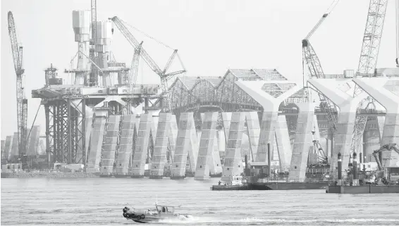  ??  ?? With the old Champlain Bridge visible in the background, constructi­on of the new $4.2-billion span over the St. Lawrence River proceeds in Montreal on Monday.