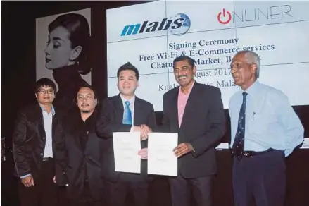  ??  ?? Onliner Co Ltd managing director Shane Suwannapha­n (third from left) exchanging documents with Mlabs System Bhd director Sureswaran Ramadass at a signing ceremony in Kuala Lumpur yesterday. PIC By HALIM SALLEH