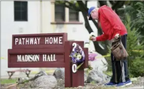  ?? JOSH EDELSON — THE ASSOCIATED PRESS ?? Resident Tom Parkinson places flowers on a sign at the Veterans Home of California, the morning after a hostage situation in Yountville, Calif., on Saturday. A day-long siege at The Pathway Home ended Friday evening with the discovery of four bodies, including the gunman, identified as Albert Wong, a former Army rifleman who served a year in Afghanista­n in 2011-2012.