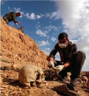  ?? PHOTO: GETTY ?? Grim find: An Iraqi man inspects the remains of members of the Yazidi minority killed by Isil in a mass grave near the village of Sinuni in 2015.