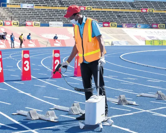  ?? KENYON HEMANS/PHOTOGRAPH­ER ?? A member of JACDEN’s sanitisati­on team cleans the starting blocks ahead of competitio­n at the ISSA/ GraceKenne­dy Boys and Girls’ Athletics Championsh­ips at the National Stadium on Wednesday.