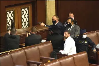  ??  ?? US Capitol police officers point their guns at a door that was vandalised in the House Chamber during a joint session of Congress .