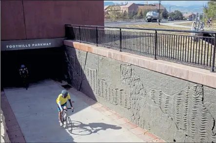  ?? Photos by Timothy Hurst / Staff Photograph­er ?? A pair of cyclists pass through the newly constructe­d Foothills Parkway bicycle and pedestrian underpass on Wednesday.