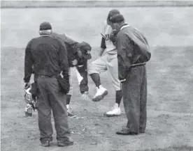  ??  ?? Rocky Mountain baseball coach Scott Bullock checks Kalen Hammer’s cleats Monday as mud starts to build up on them during a Class 5A state tournament game against Mountain Vista at All-City Field. The umpires suspended the game because of rain, and it will resume Tuesday at Metro State.