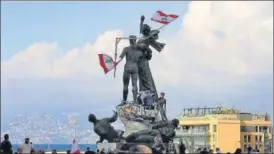  ?? REUTERS ?? Protesters fix Lebanese flags to the Martyrs' Monument at Martyrs' Square in Beirut on Sunday. n