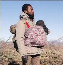  ?? D A LT O N B E N N E T T / T H E A S S O C I AT E D P R E S S F I L E S ?? A man from the Ivory Coast carries a baby near the village of Udovo, Macedonia, this month.