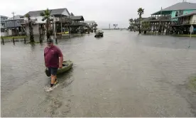  ?? Photograph: David J Phillip/AP ?? Bubba Ferguson drags a boat through a flooded street in the aftermath of Hurricane Nicholas on Tuesday in San Luis Pass, Texas.