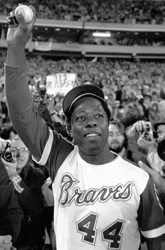  ??  ?? The Braves’ Hank Aaron holds aloft the ball he hit for his 715th career home run to break Babe Ruth’s record on April 8, 1974.