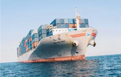  ?? COLEY BROWN/THE NEW YORK TIMES ?? One container ship among many anchored recently outside the Port of Los Angeles. Massive vessels now dominate global shipping: 133 ships that can carry 18,000 or more containers are now in service, and another 53 are on order.