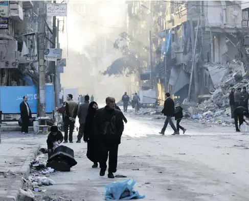  ?? LOUAI BESHARA / AFP / GETTY IMAGES ?? Syrians walk past destroyed buildings in Aleppo’s formerly rebel-held al-Shaar neighbourh­ood on the weekend, a month after government forces retook the northern Syrian city from rebel fighters. Russia, Turkey and Iran have inked an agreement to monitor...