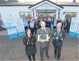  ?? Picture: Dougie Nicolson. ?? Mr Reynolds, front, centre, with a special cake, Laura Carr and Peter Strain, both holding the awards, and the firm’s staff.