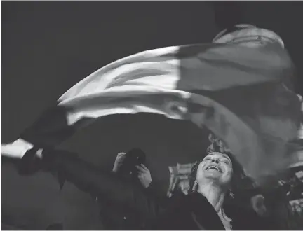  ?? PASCAL LE SEGRETAIN/GETTY IMAGES ?? A woman waves the French flag in Republic Square in Paris on Friday. Parisians are standing resolute in the aftermath of last week’s terror attacks, vowing that despite a year of tragedy, they will not live in fear.